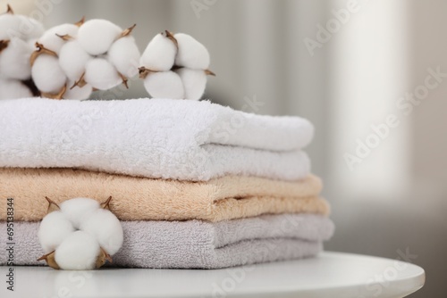 Terry towels and cotton branch with fluffy flowers on white table indoors, closeup. Space for text