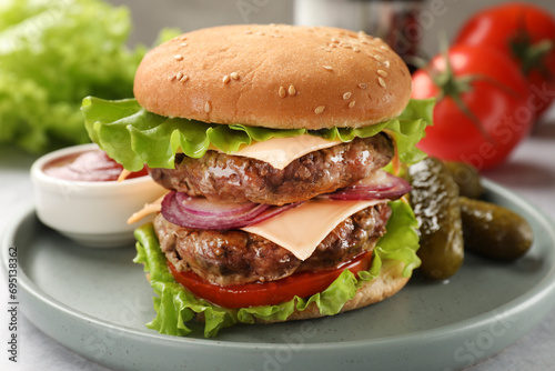 Tasty hamburger with patty, cheese and vegetables served on table, closeup