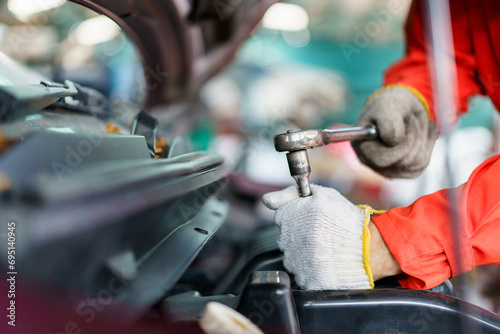 Automobile technician working in auto garage, technician holding a wrench preparing to repair broken vehicle. 