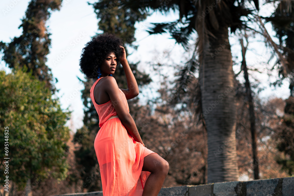 beautiful black woman with orange dress enjoying a sunny day, full, thoughtful and melancholic in a park in the city beautiful black woman with orange dress enjoying a sunny day, full, thoughtful and melancholic in a park in the city
