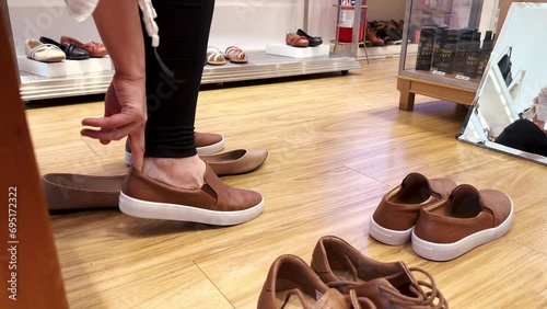 Lady in a shoe shop trying new pairs of comfortable shoes, sneakers photo