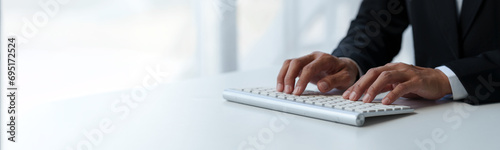 Cropped view of businessman typing on keyboard Hand typing on wireless computer keyboard and mouse in office, writing, typing email or communicating online. copy space, banner , panorama photo