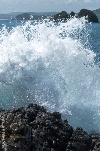  Waves crash against the rugged volcanic rocks, the power of nature. Indonesia, Asia. photo