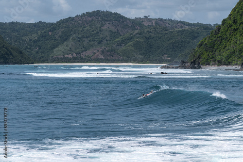 Lone surfer paddles out in the tranquil waters of Mawi Beach, Lombok, Indonesia, Asia photo