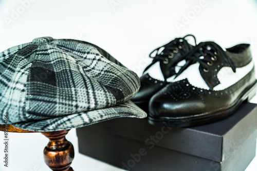 Classic studio photo concept of vintage genuine leather shoes with newsboys hat or scaly hat on bronze mannequin on isolated white background photo