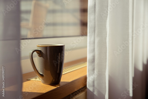 A cup of coffee on the window sill of the hotel in the light of the sun