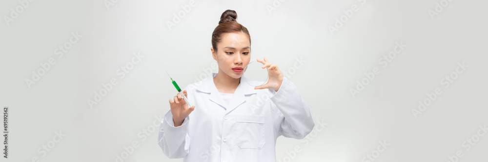 Young female doctor looking at liquid sample in petri dish on isolated background Young female doctor looking at liquid sample in petri dish on isolated background