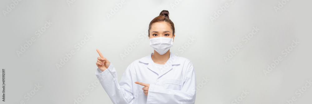Asian nurse or doctor woman wearing medical face mask pointing fingers Asian nurse or doctor woman wearing medical face mask pointing fingers