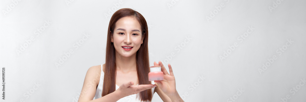 Smiling young beauty asian woman showing skincare products isolated on banner background. Smiling young beauty asian woman showing skincare products isolated on banner background.