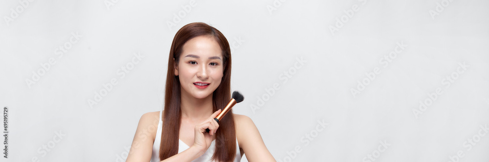 beautiful happy young girl with perfect skin is holding makeup brush in hand over banner background beautiful happy young girl with perfect skin is holding makeup brush in hand over banner background