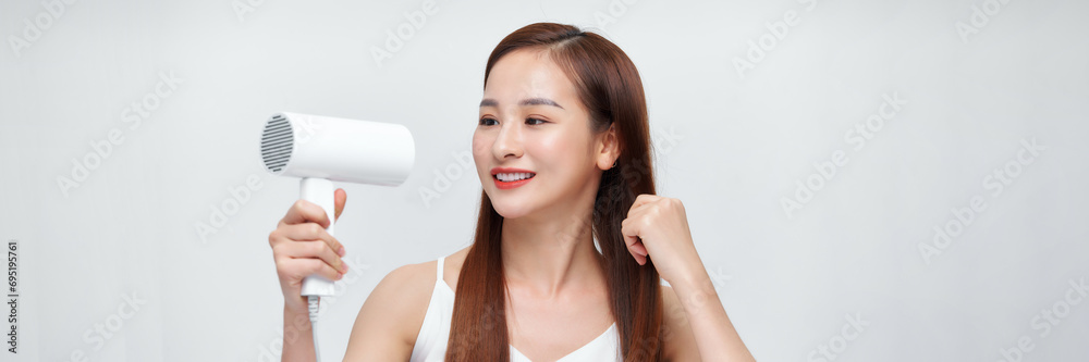 A cute young girl dries her beautiful long silky hair with a hair dryer. Banner A cute young girl dries her beautiful long silky hair with a hair dryer. Banner