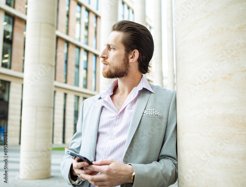 Young business man talking on phone near modern office building.