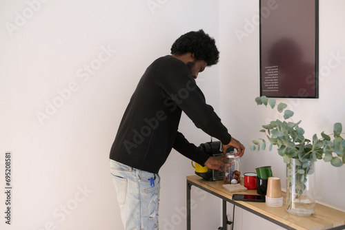 Morning Routine with Espresso. Black man preparing coffee in a serene home setting. photo