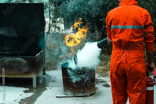 stcw firefighting prevention training, man using fire extinguisher against open fire in a barrel, maritime courses photo