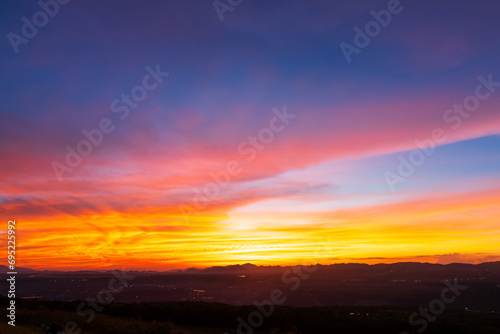 Twilight blue bright and orange yellow dramatic sunset sky in countryside or beach colorful cloudscape texture with white clouds air background. © Thinapob