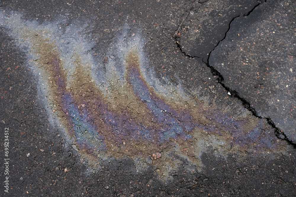 Obraz premium Leakage of oil or gasoline from the car on the asphalt in the parking lot.