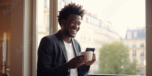 A man is seen holding a cup of coffee while gazing out of a window. This image can be used to depict a moment of relaxation or contemplation photo