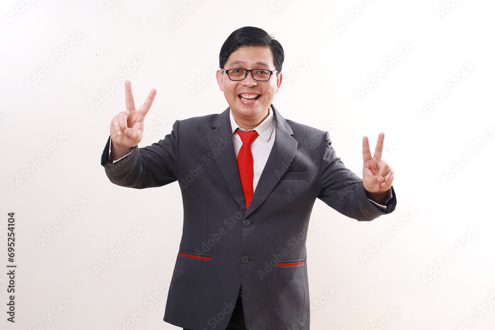 Happy excited asian businessman standing while showing victory hand gesture. Isolated on white Happy excited asian businessman standing while showing victory hand gesture. Isolated on white