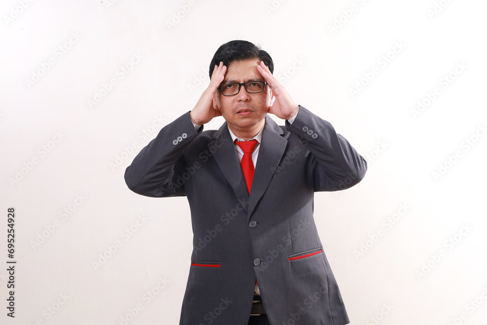 Stressed asian businessman standing while holding head. Isolated on white Stressed asian businessman standing while holding head. Isolated on white