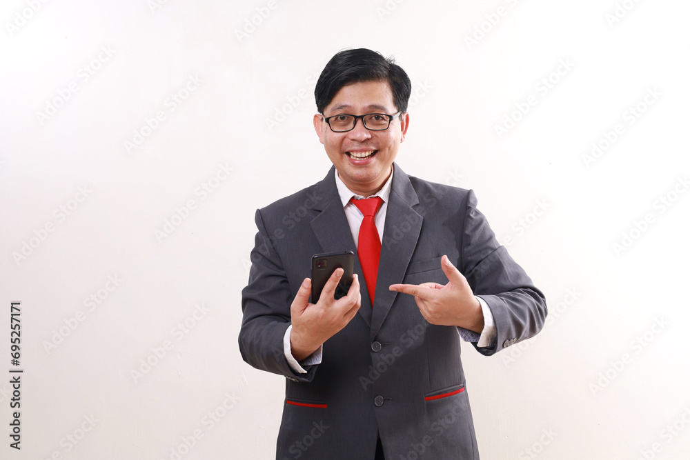 Excited asian businessman showing a blank cell phone screen while pointing on it. Isolated on white Excited asian businessman showing a blank cell phone screen while pointing on it. Isolated on white