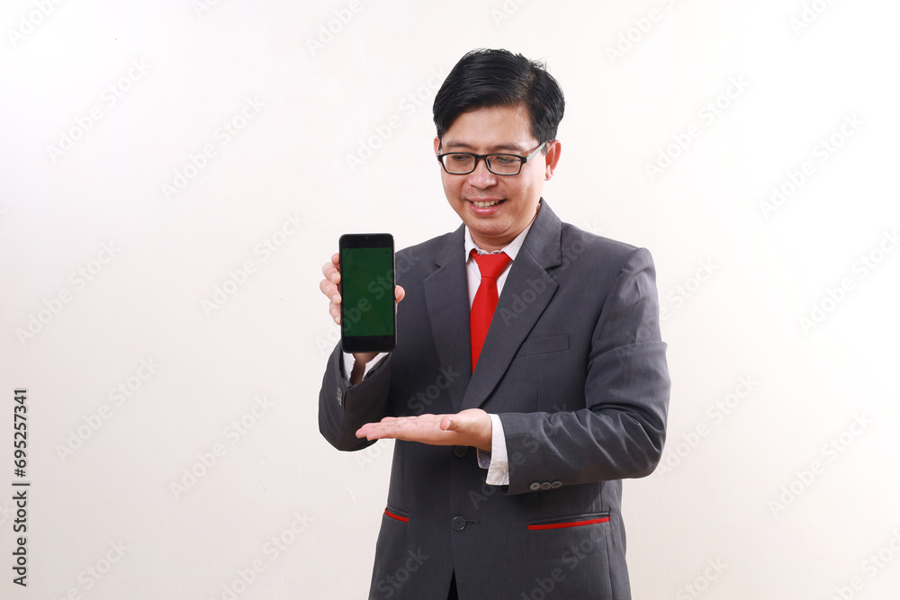Happy asian businessman standing while showing blank cell phone display. Isolated on white Happy asian businessman standing while showing blank cell phone display. Isolated on white