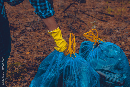 A woman volunteer puts together bags of garbage collected from the forest. A woman has collected a lot of household waste in garbage bags in the forest and is preparing it for removal. Ecology.
