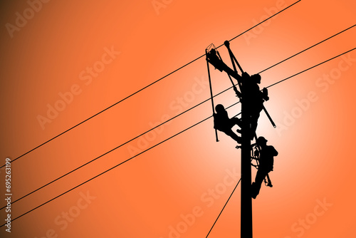 The silhouette of lineman are replacing damaged insulator insulators by using insulated wire-tong sets, tie stick and robe box sets in sliding wires going out in a safety working distance. photo