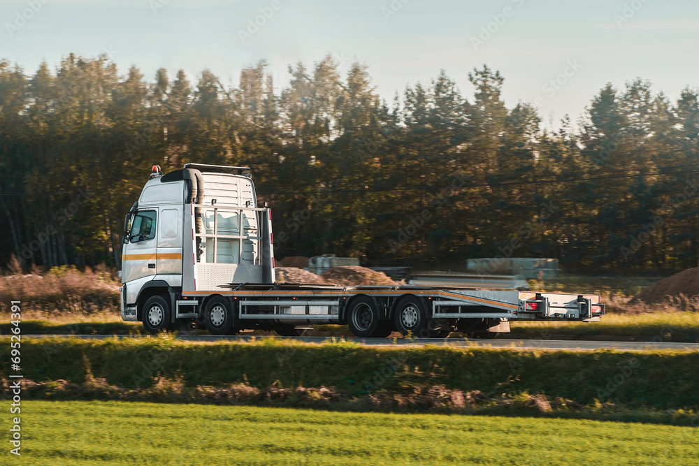 A tow truck carries a broken car on the highway in bad weather. Roadside assistance helps a driver in trouble. Rollback tow truck.