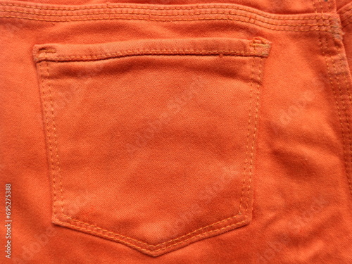 Close up of the back pocket of orange jeans
