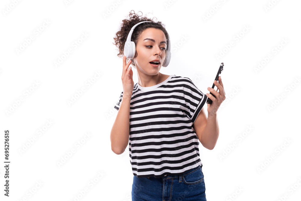 young positive curly brunette woman music lover in a striped casual t-shirt with headphones dancing young positive curly brunette woman music lover in a striped casual t-shirt with headphones dancing