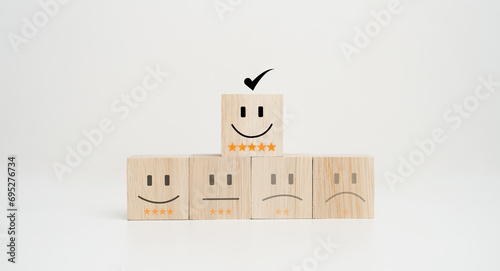 Customer service evaluation and satisfaction survey concepts. The happy face smile face icon and five star symbol on wooden cube on table.