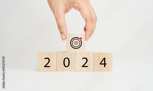 Happy new year 2024, goal and success with business, environmental sustainability concepts. Target dart icon and 2024 year number on cube wooden cube blocks on wood table and white background.