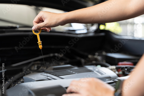 Close up of woman's hands checking oil level in car engine Woman checking oil level in car engine at home.