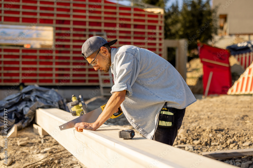 Carpenter works on a construction site, building a frame house in mountains Carpenter works on a construction site, building a frame house in mountains