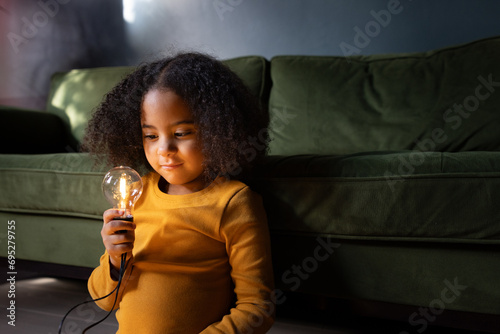 Girl looking at a lightbulb in evening light smiling photo
