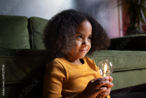 Girl holding a lightbulb in evening light smiling photo