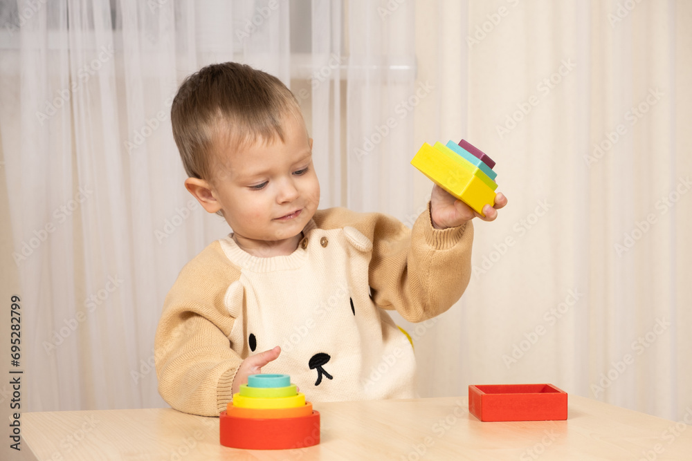 A two-year-old boy plays with wooden toys to develop logic and motor skills A two-year-old boy plays with wooden toys to develop logic and motor skills