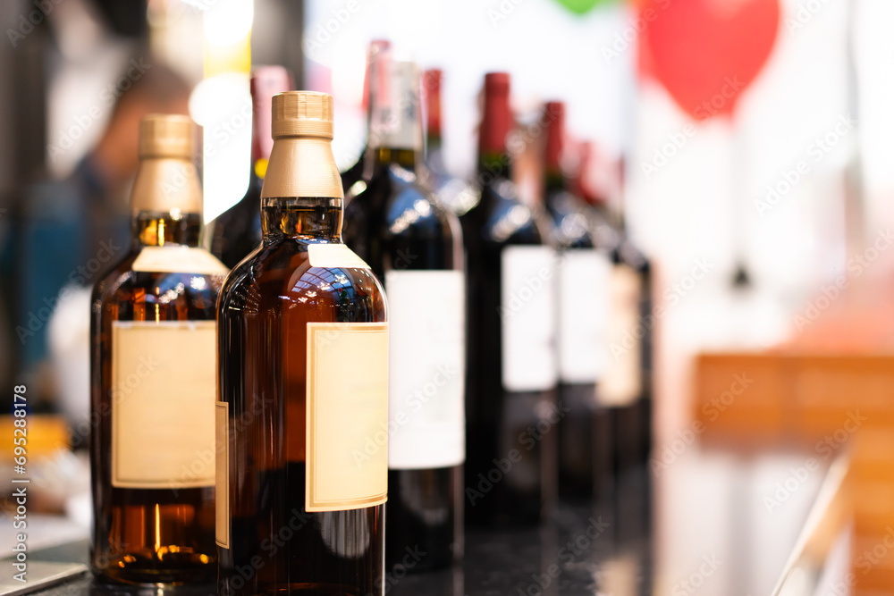 Whiskey bottles lined up on a bar, bokeh light background