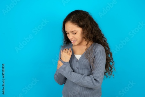 Beautiful teen girl wearing blue jacket over blue background Suffering pain on hands and fingers, arthritis inflammation photo