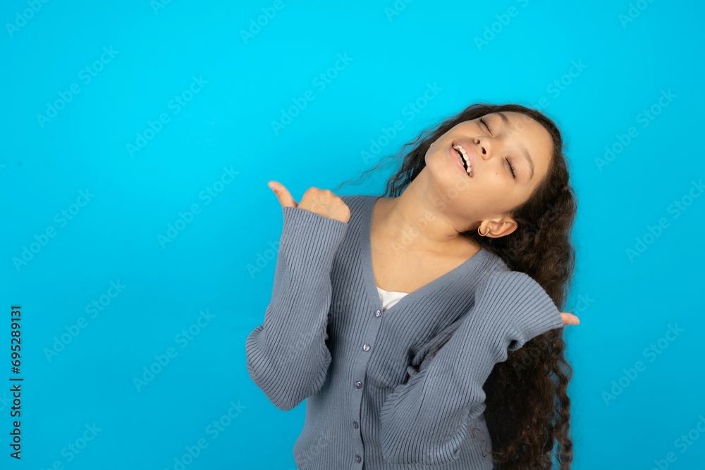 Beautiful teen girl wearing blue jacket over blue background celebrating surprised and amazed for success with arms raised and eyes closed. Winner concept.