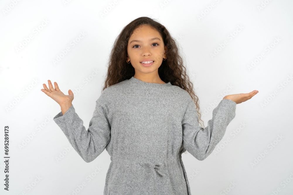 Cheerful cheery optimistic Beautiful teen girl wearing grey dress over white background holding two palms copy space Cheerful cheery optimistic Beautiful teen girl wearing grey dress over white background holding two palms copy space