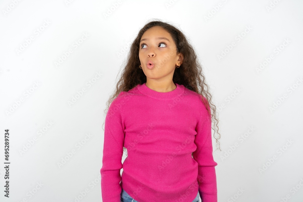 Shocked Beautiful teen girl wearing pink sweater over white background look empty space with open mouth screaming: Oh My God! I can't believe this. Shocked Beautiful teen girl wearing pink sweater over white background look empty space with open mouth screaming: Oh My God! I can't believe this.