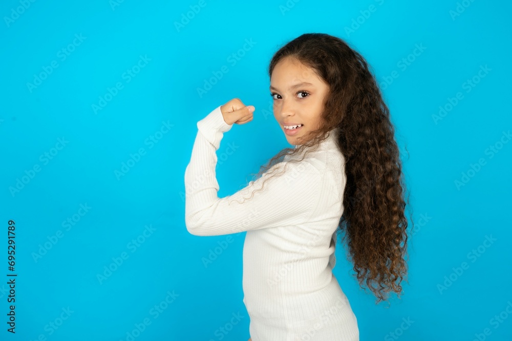 Profile side view portrait Young beautiful teen girl wearing white turtleneck over blue background celebrates victory Profile side view portrait Young beautiful teen girl wearing white turtleneck over blue background celebrates victory