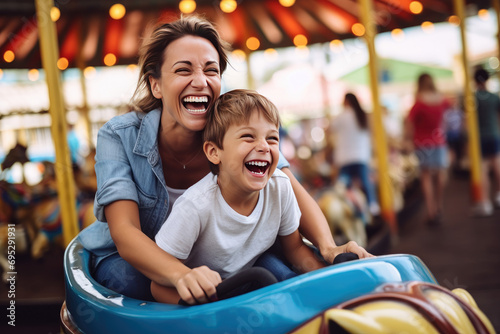Joyful mother and son enjoying a fun summer, riding a bumper car at an amusement park