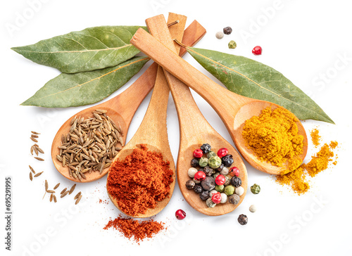Colorful different seasonings in wooden spoons surrounded with herbs and spices on white background. photo