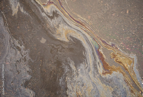 Rainbow-colored oil floating on water after rain on asphalt.