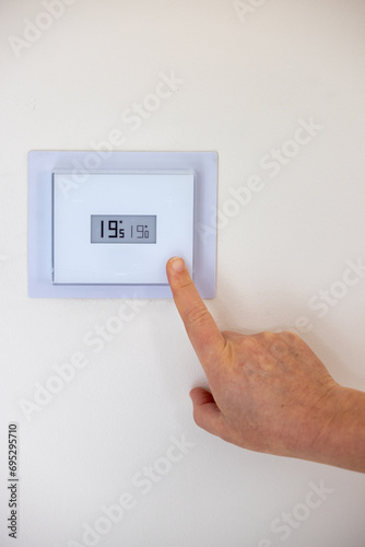 Person adjusting the temperature of their thermostat