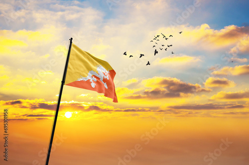 Waving flag of Bhutan against the background of a sunset or sunrise. Bhutan flag for Independence Day. The symbol of the state on wavy fabric. photo