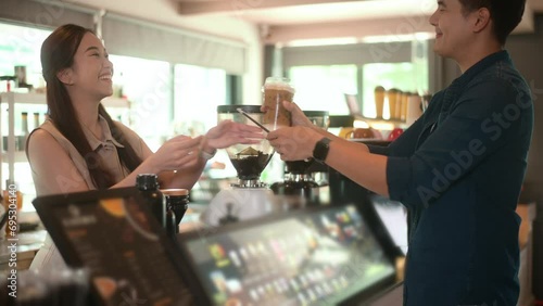 Young Asian service minded barista  with customer in coffee shop