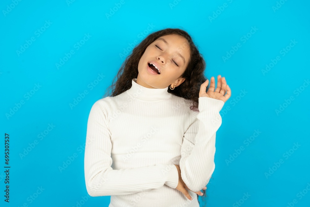 Overjoyed successful Young beautiful teen girl raises palm and closes eyes in joy being entertained by friends Overjoyed successful Young beautiful teen girl raises palm and closes eyes in joy being entertained by friends